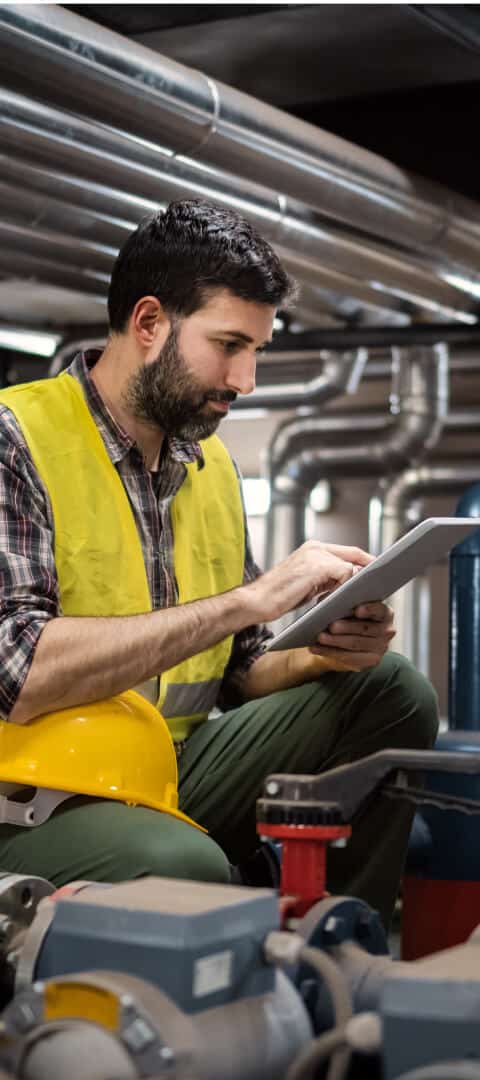 A man monitoring production on a tablet in a factory.