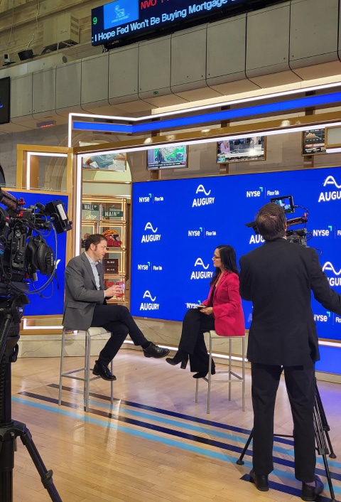 A group of people on a stage in front of a camera at the Media Center.