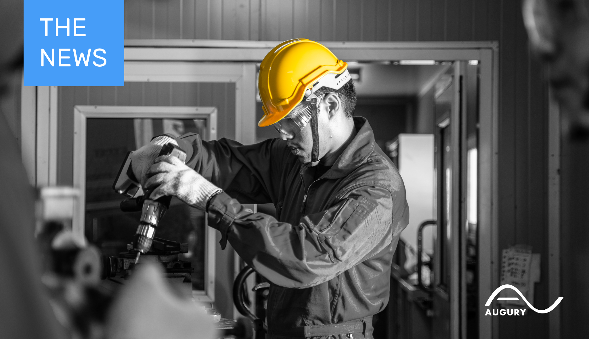 A man in a hard hat is working on a machine in manufacturing.