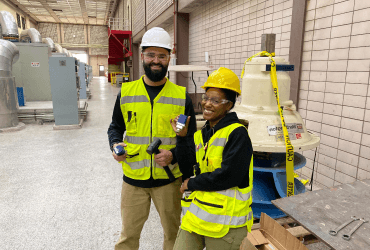 Two construction workers in a warehouse.