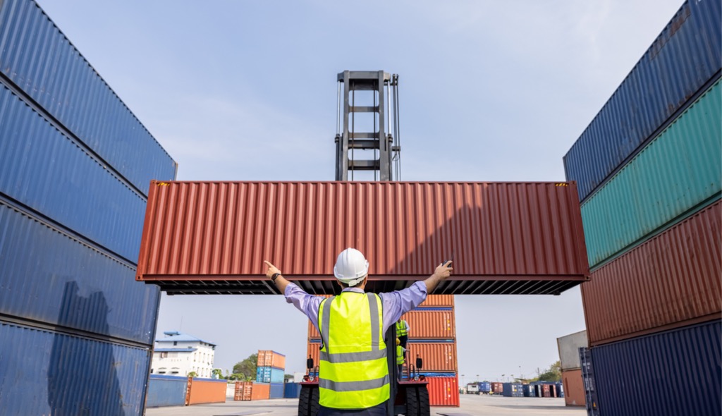 Worker helps guide shipping container