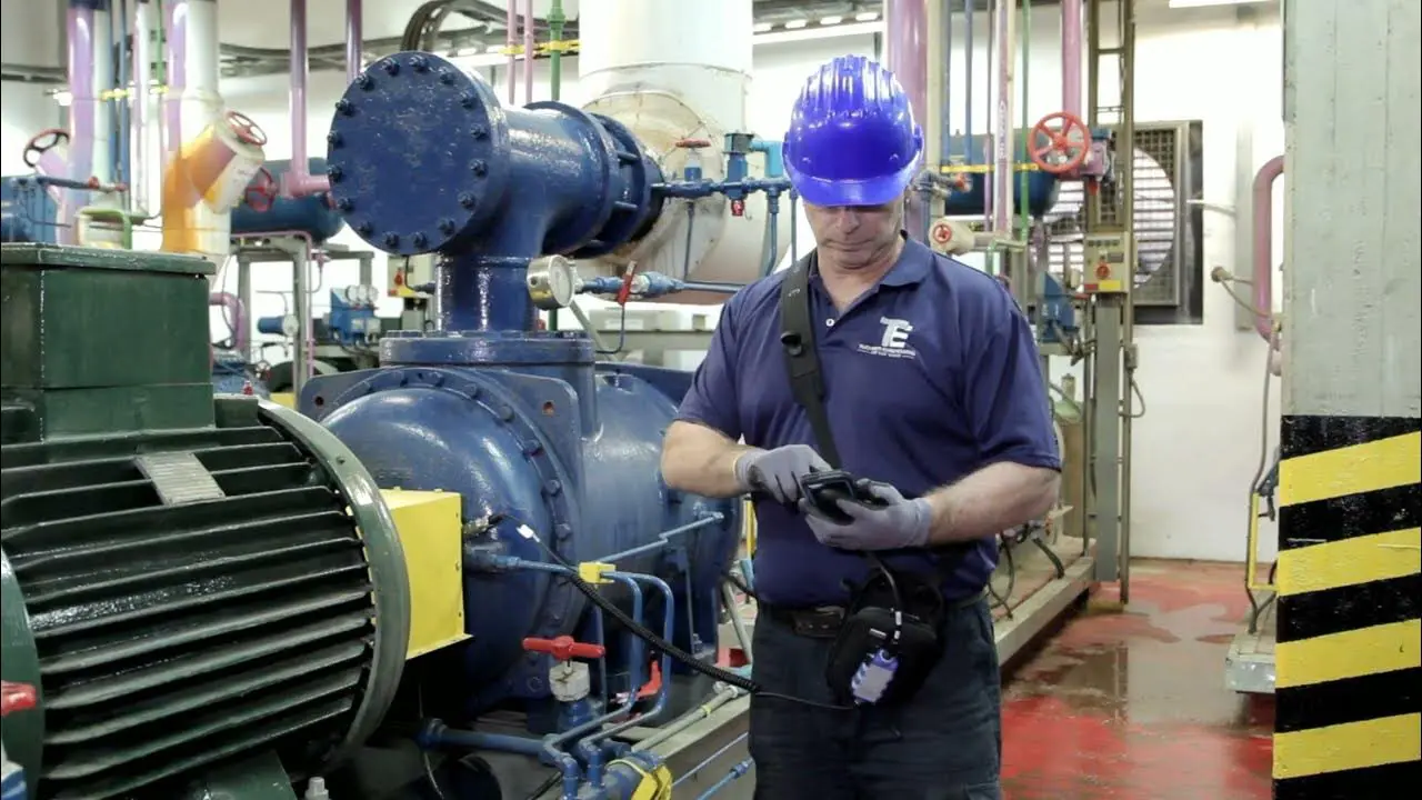 A man is standing in front of a large machine, learning how to transform his HVAC skills into vibration analysis for predictive maintenance.