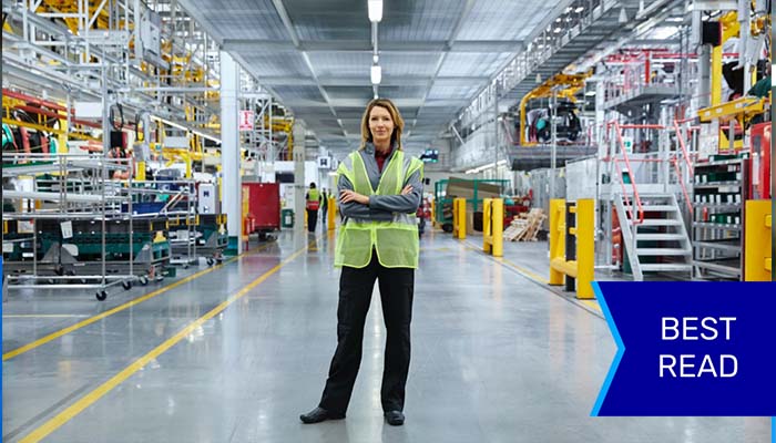 Woman standing confidently in middle of factory floor.