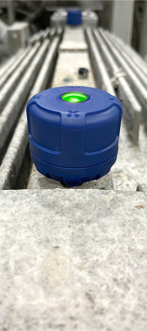 A machine health indicator showcasing a blue button with a green light on top of a metal surface.