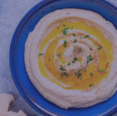 Hummus in a blue bowl on a table.