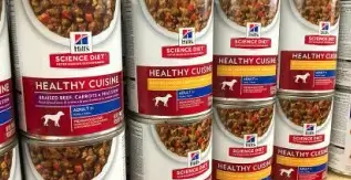 A row of cans of dog food on a shelf.