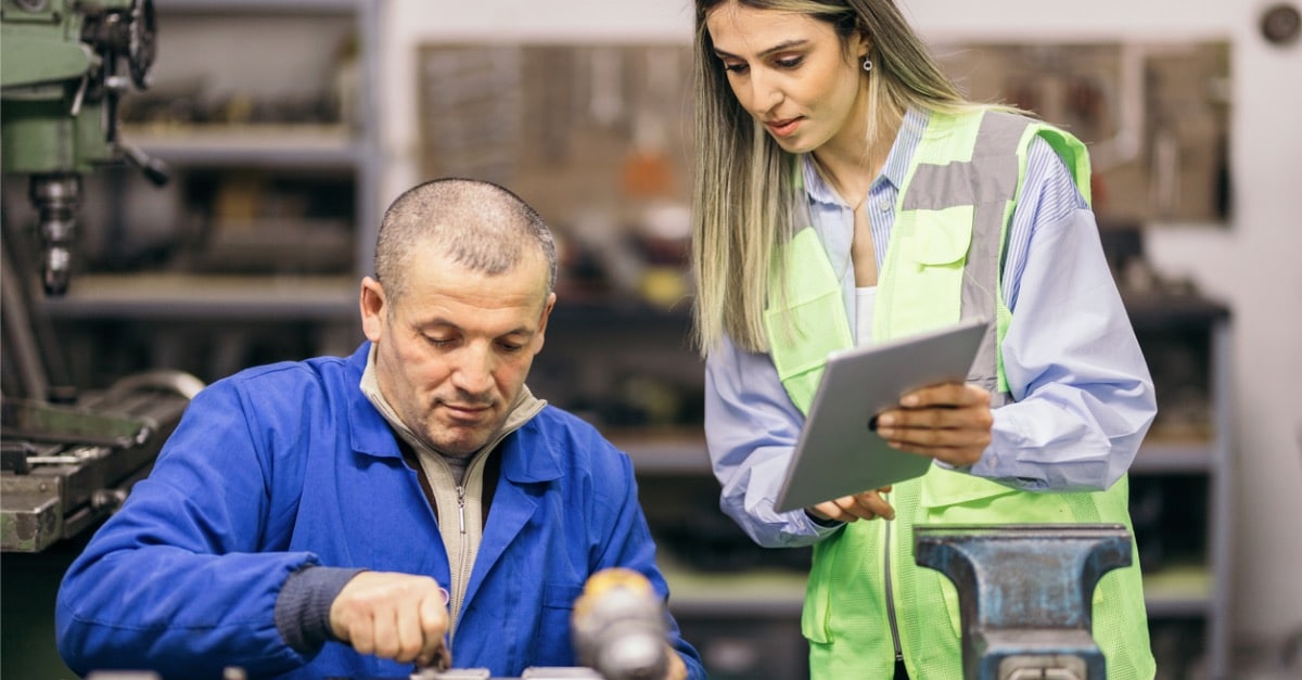 Female engineer working on production process with metal worker