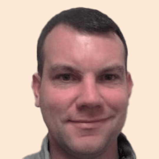 A man named Adam Kilgore smiling in front of a beige background.