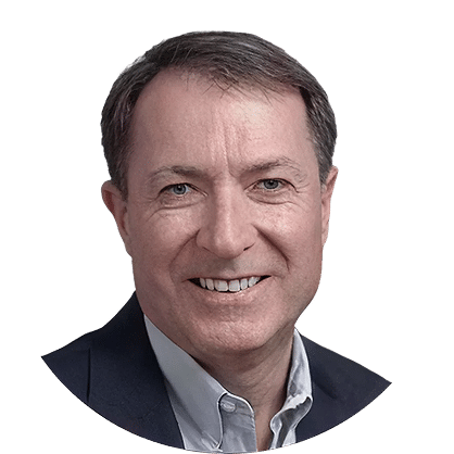 A middle-aged man with short brown hair, wearing a dark blazer over a light-colored collared shirt, smiling at the camera against a plain white background.