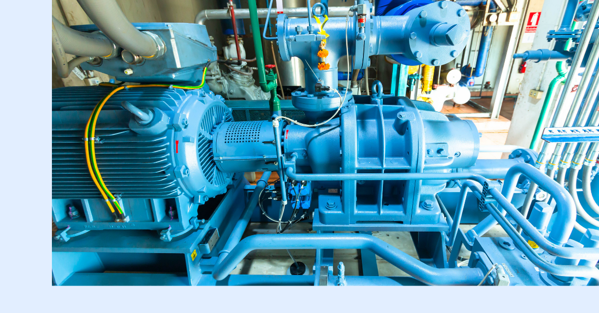 Blue industrial machinery featuring an electric motor connected to a pump with attached pipes, wires, and gauges, situated in a clean, well-lit mechanical room.