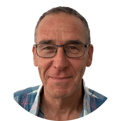A smiling older man with short gray hair and glasses, wearing a plaid shirt, shown against a plain white background.