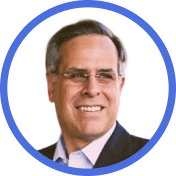 A middle-aged man with short dark hair, glasses, and a suit smiles while looking to the side, framed by a blue circular border on a white background.