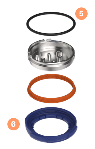 Exploded view of a mechanical assembly showing four parts: a black O-ring labeled 5, a metal circular part, an orange ring, and a blue plastic ring labeled 6, all aligned vertically.