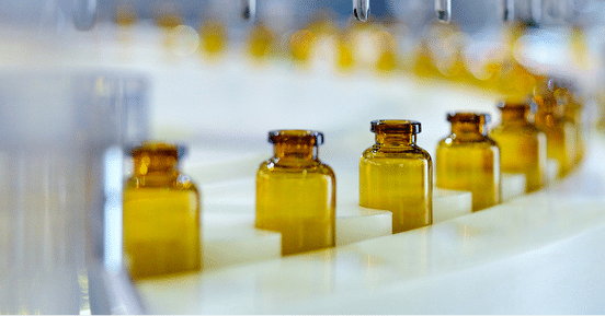 Amber glass vials arranged in a production line setup, ready to be filled by machinery in a pharmaceutical environment, ensuring optimal machine health—a critical focus for leading pharma companies.