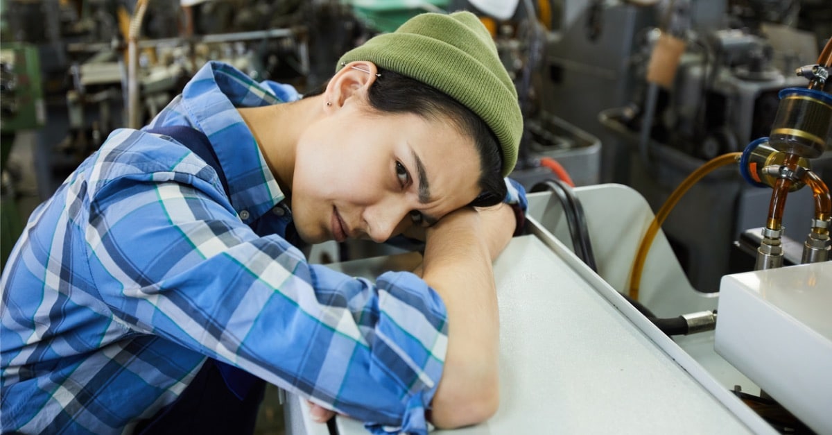 Female factory maintenance worker holding head and looking confused