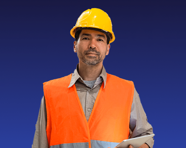 A construction worker wearing an orange safety vest and yellow hard hat holds a tablet, standing in front of a plain dark blue background.