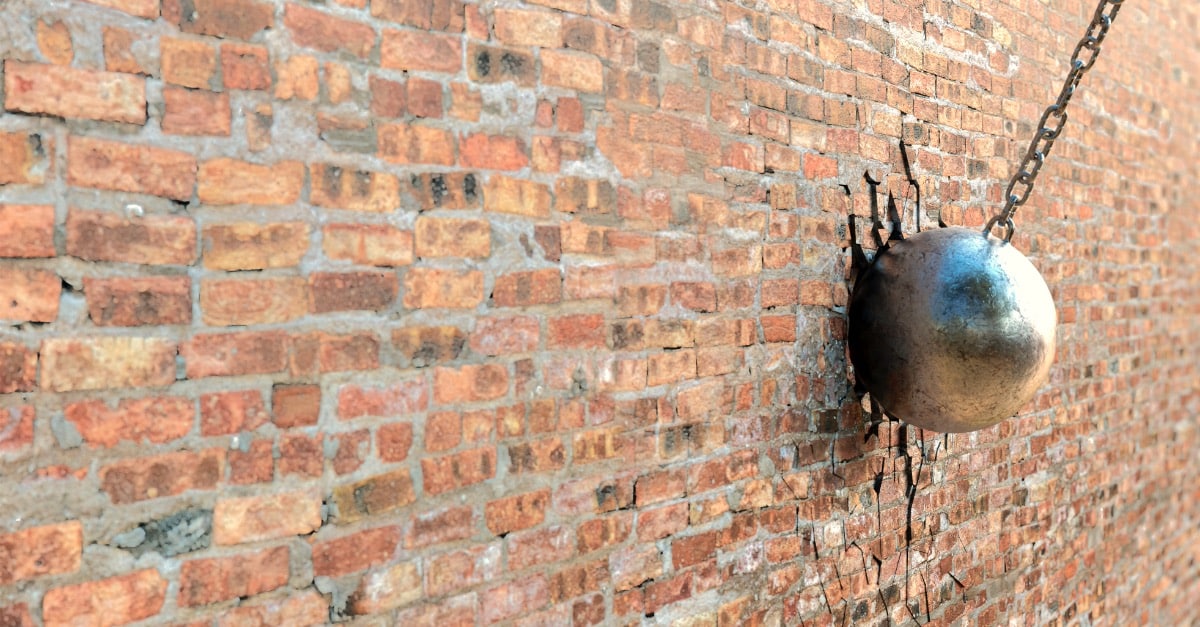 A wrecking ball hitting a brick wall representing the bringing together of Maintenance & Operations